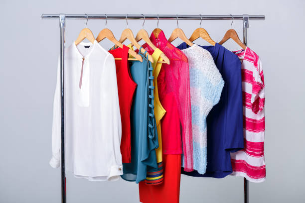 colorful womens clothes on wood hangers on rack on gray background. women's closet